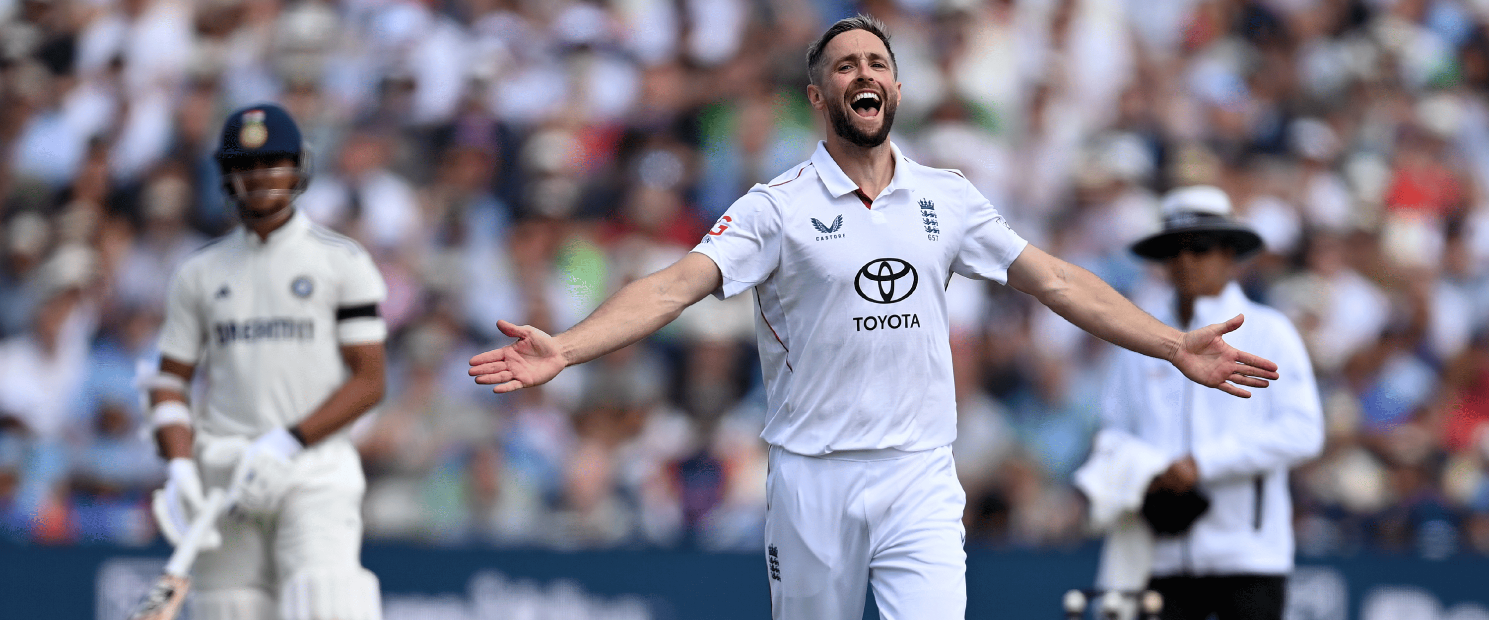 England cricketer Chris Woakes smiling and celebrating in a Test match with his arms in the air